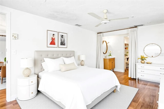 bedroom featuring ceiling fan, visible vents, wood finished floors, and ensuite bathroom