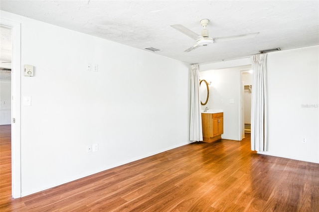 unfurnished room with visible vents, ceiling fan, and wood finished floors