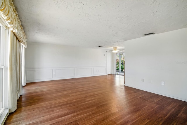 unfurnished room featuring wood finished floors, visible vents, and a textured ceiling