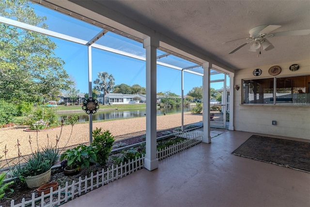 unfurnished sunroom featuring ceiling fan and a water view