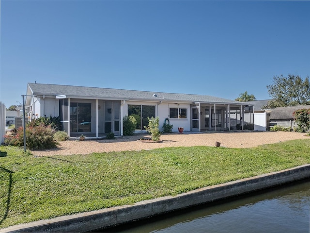 rear view of property featuring a lawn, a water view, and a sunroom