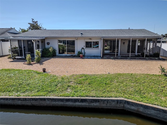 rear view of house featuring a lawn, a water view, and a sunroom