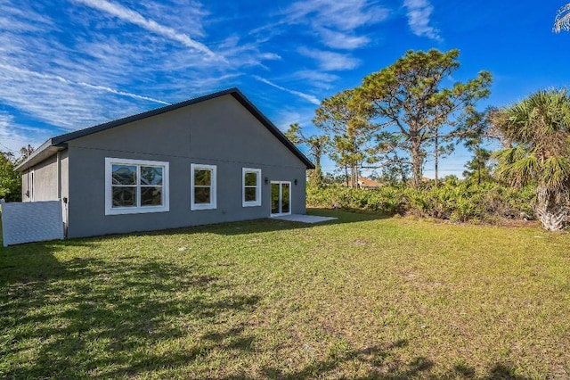 rear view of house with stucco siding and a yard