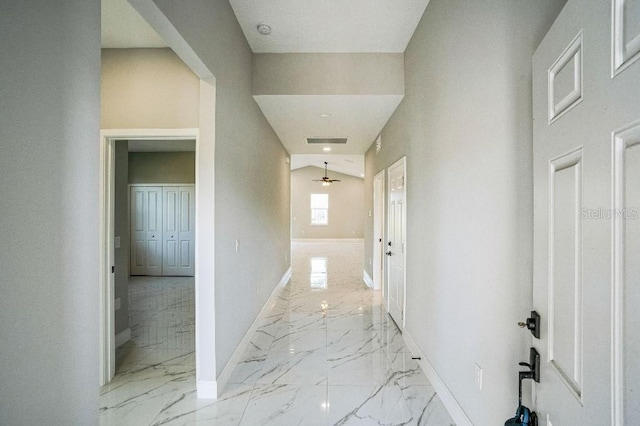 hallway featuring visible vents, baseboards, marble finish floor, and vaulted ceiling