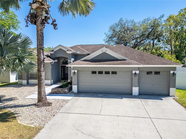 view of front facade featuring a shingled roof, an attached garage, driveway, and stucco siding