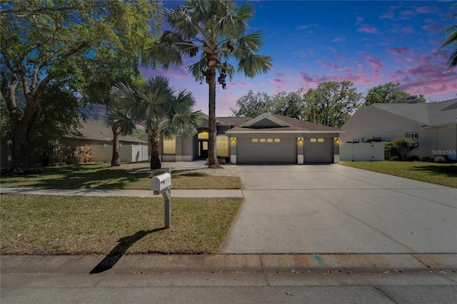 view of front of property with fence, a front yard, stucco siding, driveway, and an attached garage