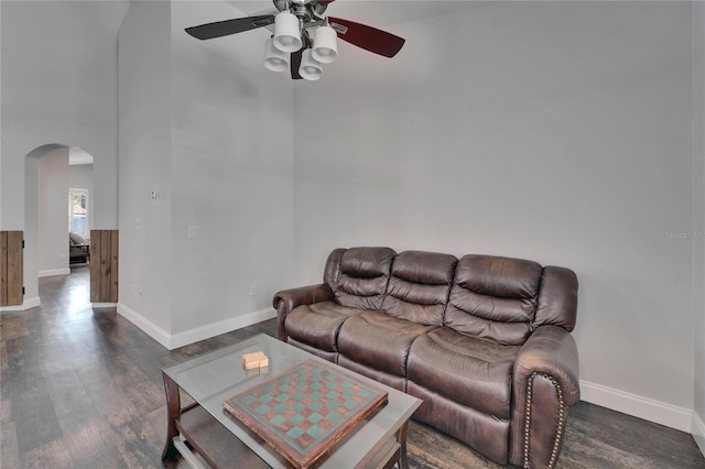 living area with ceiling fan, wood finished floors, arched walkways, and baseboards