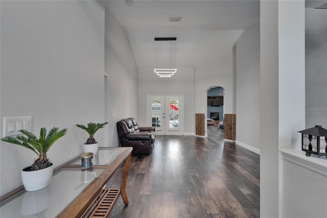 foyer entrance with visible vents, dark wood finished floors, french doors, a high ceiling, and a fireplace