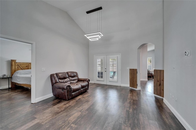 living area featuring baseboards, french doors, wood finished floors, arched walkways, and high vaulted ceiling