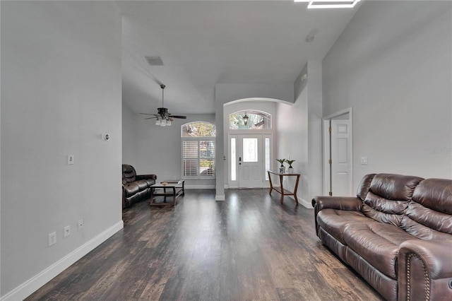 living area with wood finished floors, visible vents, baseboards, a high ceiling, and ceiling fan