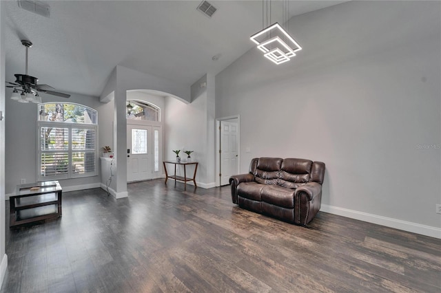 living area with visible vents, baseboards, high vaulted ceiling, and wood finished floors