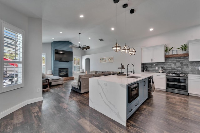 kitchen featuring pendant lighting, a sink, double oven range, dark wood-style floors, and a fireplace