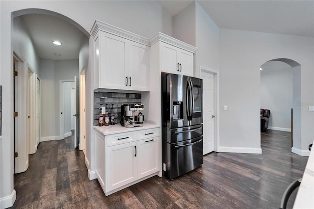 kitchen with arched walkways, tasteful backsplash, stainless steel fridge with ice dispenser, and light countertops