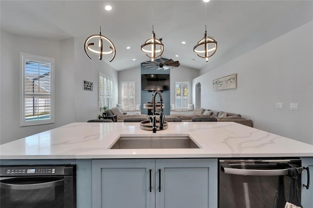 kitchen featuring gray cabinets, a sink, light stone counters, stainless steel dishwasher, and open floor plan