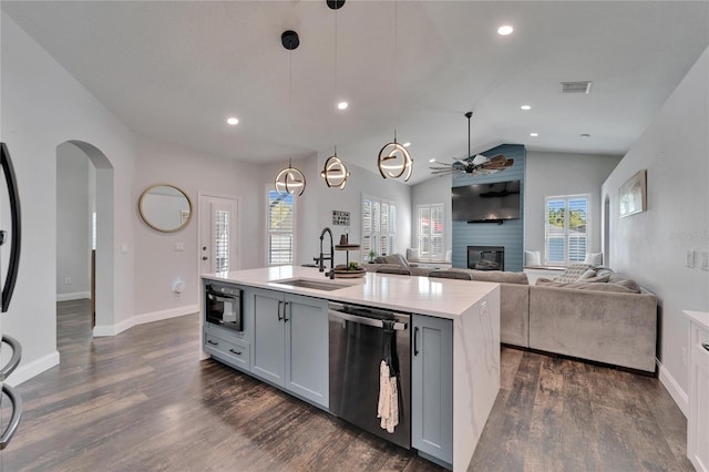 kitchen with a sink, dark wood finished floors, a fireplace, light countertops, and dishwasher