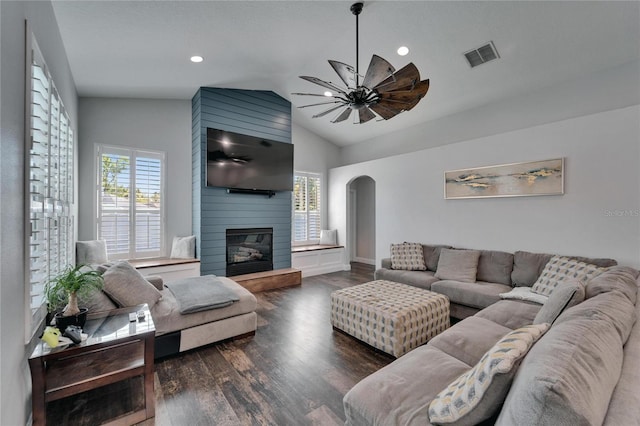 living room featuring visible vents, vaulted ceiling, a fireplace, wood finished floors, and arched walkways