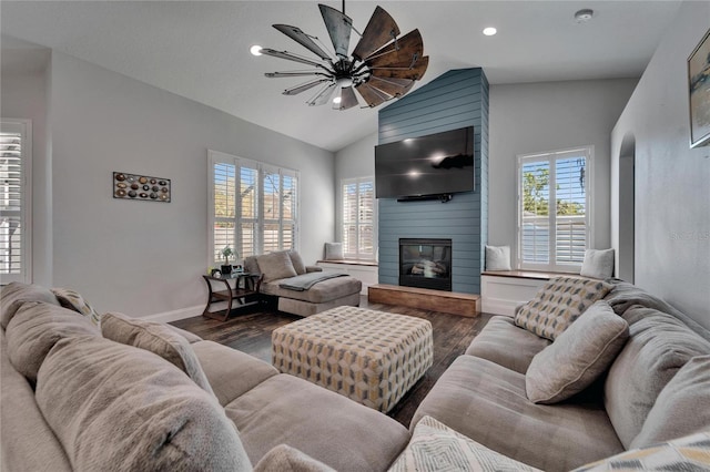 living area featuring dark wood finished floors, baseboards, a large fireplace, and lofted ceiling