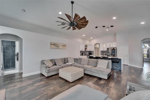 living area with dark wood-style floors, recessed lighting, arched walkways, baseboards, and vaulted ceiling