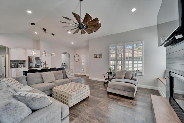 living room featuring dark wood-style floors, arched walkways, and baseboards