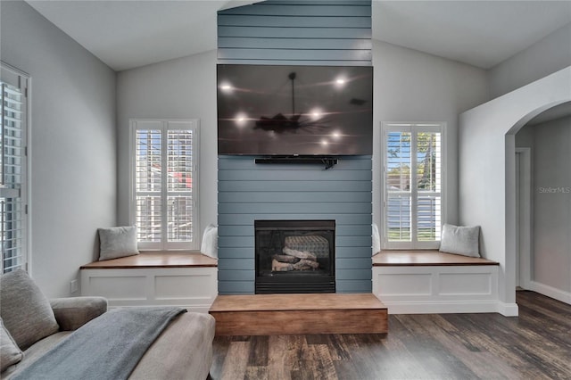 living room with arched walkways, a large fireplace, lofted ceiling, and wood finished floors