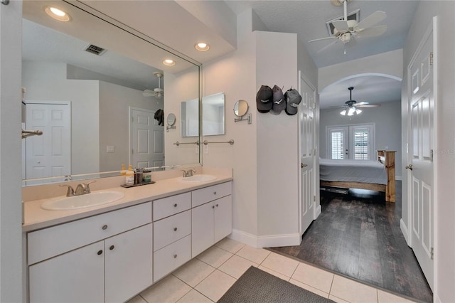 ensuite bathroom featuring tile patterned flooring, ensuite bath, double vanity, and a sink