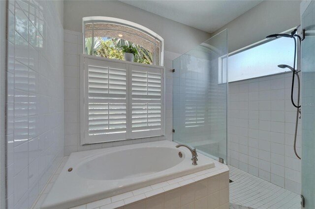 bathroom featuring a wealth of natural light, a garden tub, and a walk in shower