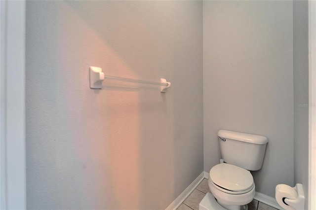 bathroom with baseboards, toilet, and tile patterned flooring