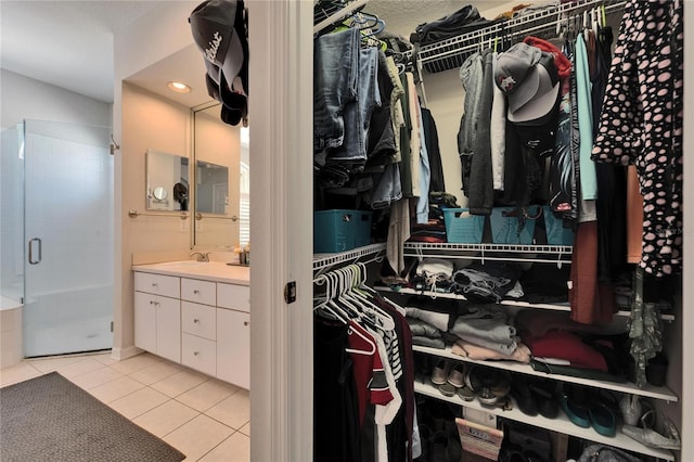 spacious closet featuring light tile patterned floors and a sink