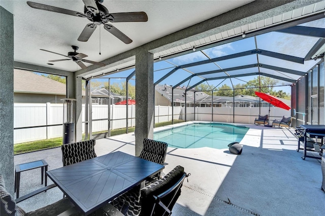 view of pool with a patio area, glass enclosure, a ceiling fan, and a fenced backyard