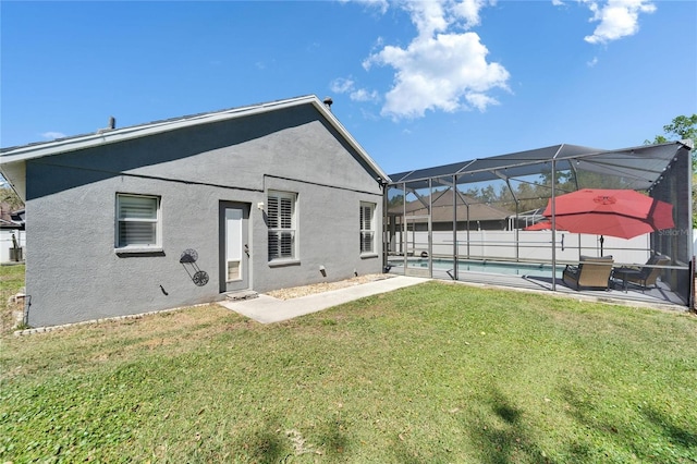 back of house with stucco siding, a yard, glass enclosure, a fenced in pool, and a patio area