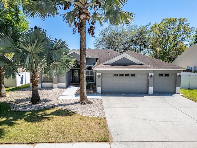 view of front facade featuring fence, an attached garage, stucco siding, concrete driveway, and a front lawn