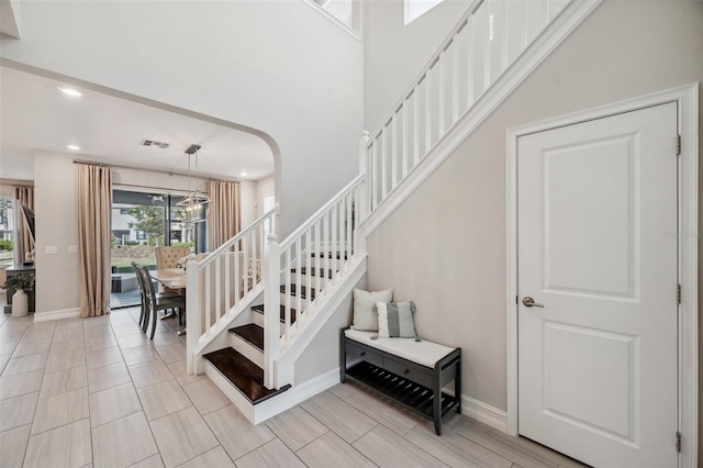 staircase with baseboards, visible vents, a high ceiling, recessed lighting, and arched walkways