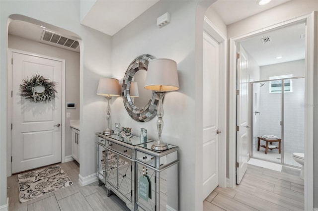 entryway featuring baseboards, arched walkways, visible vents, and wood finish floors