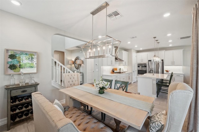 dining space with recessed lighting, visible vents, arched walkways, and an inviting chandelier