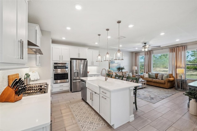 kitchen with under cabinet range hood, stainless steel appliances, light countertops, and a breakfast bar