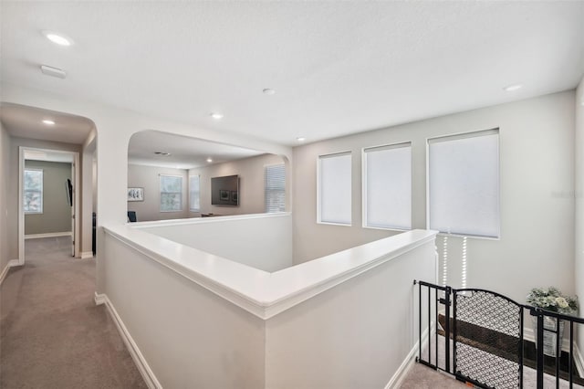 hallway with recessed lighting, baseboards, an upstairs landing, and light carpet