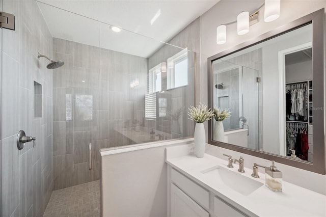 bathroom with a walk in closet, vanity, and a shower stall