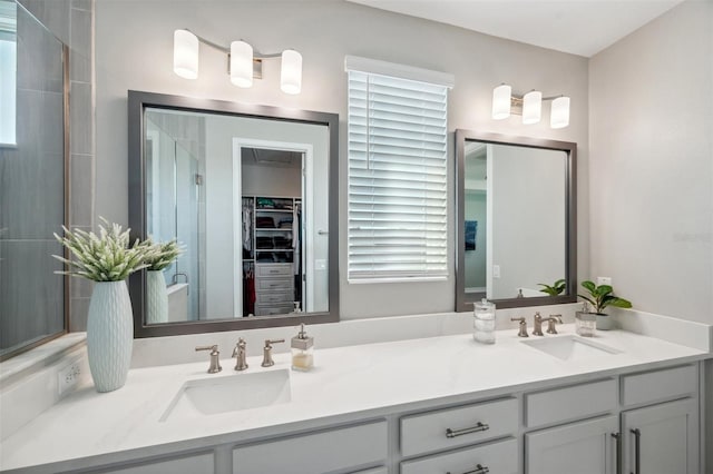 full bath featuring a sink, a walk in closet, double vanity, and a shower stall