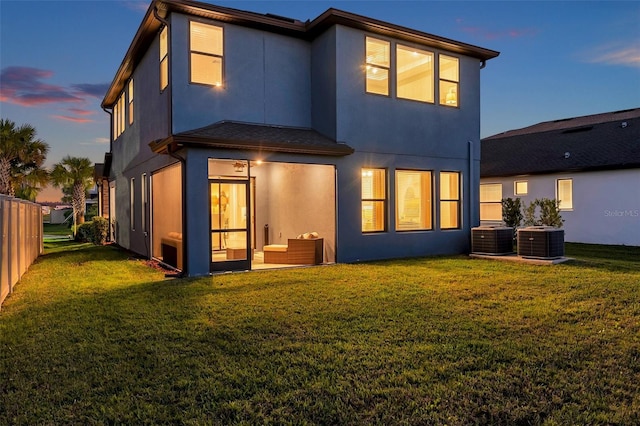 rear view of house with cooling unit, a lawn, and stucco siding