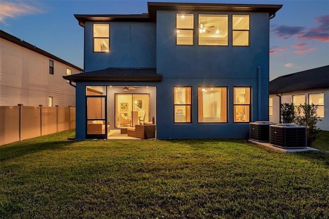 back of property featuring stucco siding, cooling unit, a yard, and fence