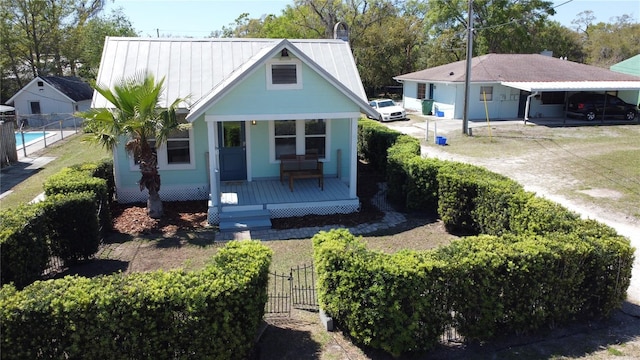 view of front of property with a porch, fence, and metal roof