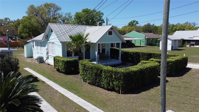 bungalow-style home featuring central AC, a front yard, covered porch, metal roof, and a standing seam roof