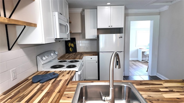 kitchen featuring backsplash, wooden counters, crown molding, white appliances, and a sink