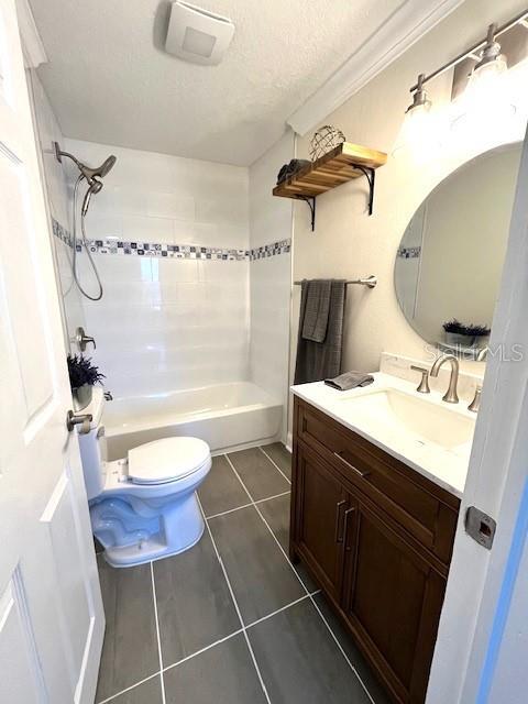 bathroom with toilet, shower / tub combination, a textured ceiling, tile patterned flooring, and vanity