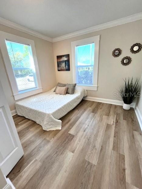 bedroom featuring wood finished floors, baseboards, and ornamental molding