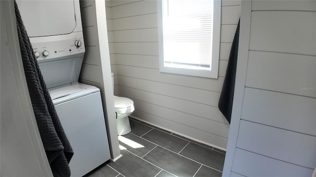 bathroom with tile patterned floors, stacked washer / dryer, and toilet