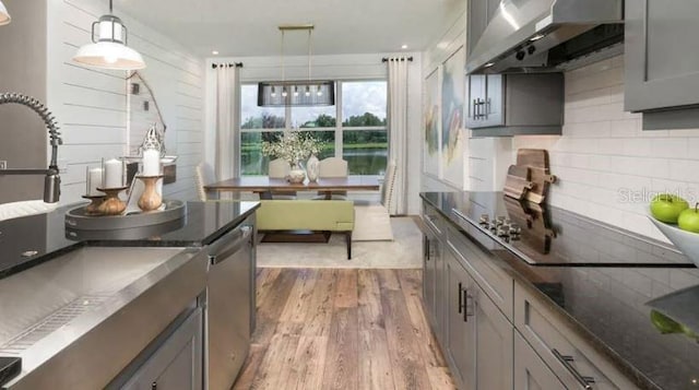 kitchen featuring gray cabinetry, dark wood-type flooring, wall chimney range hood, dishwasher, and decorative backsplash