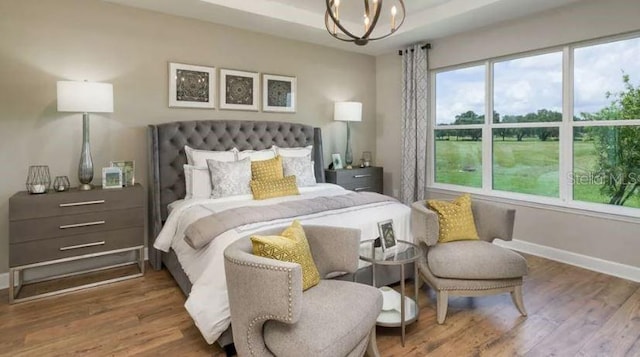 bedroom featuring a chandelier, baseboards, and wood finished floors