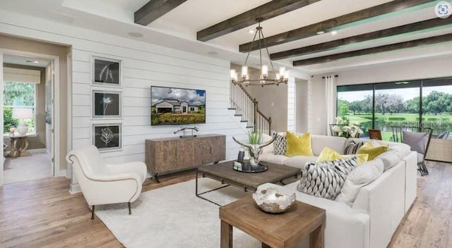 living area featuring beam ceiling, wooden walls, an inviting chandelier, and light wood finished floors