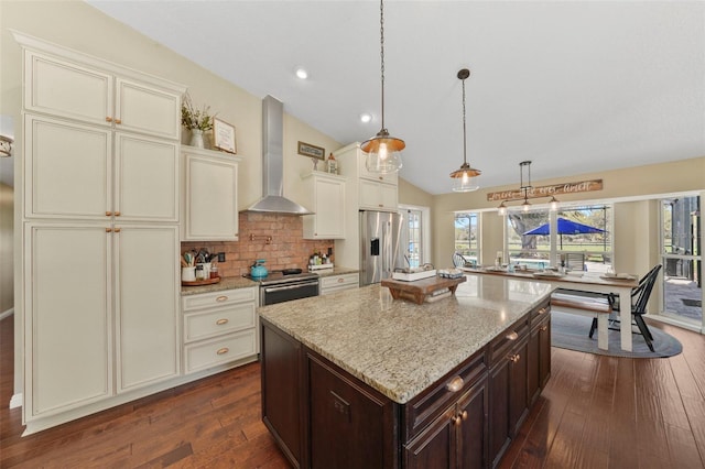 kitchen with vaulted ceiling, dark wood-type flooring, dark brown cabinetry, appliances with stainless steel finishes, and wall chimney exhaust hood